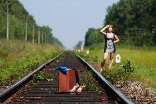 girl on the railroad track with suitcase