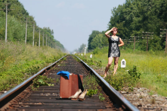 girl on the railroad track with suitcase