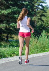 Young woman jogging in the park. Back view.