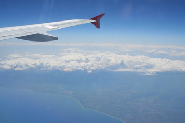 Fototapeta na wymiar View of jet plane wing with land and sea below