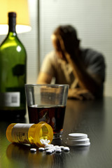 Depressed man with wine and prescription medication, vertical