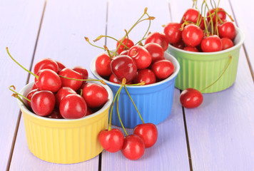 Cherry berries in bowls on wooden table close up