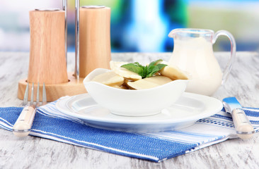 Tasty dumplings on white plate, on bright background
