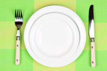 Knife, color plate and fork, on color background