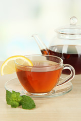 Cup of tea with lemon on table on light background
