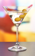 Martini with green olives on table in bar