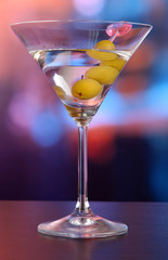 Martini with green olives on table in bar