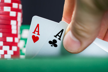 Poker player lifting the corners of two cards