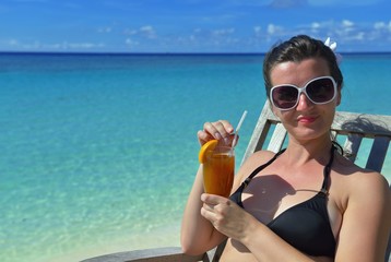 Beautiful young woman with a drink by the sea