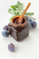Plums beside open jar of plum jam