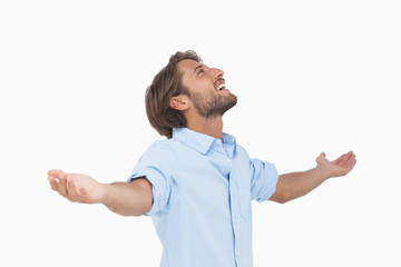 Happy man looking up with arms outstretched