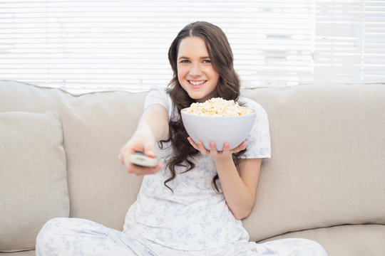 Pretty woman in pyjamas having popcorn while watching tv