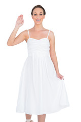 Naklejka premium Smiling beautiful young model in white dress waving