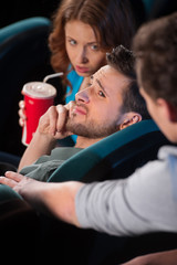 Talking at phone in cinema. Young men talking at phone while wat