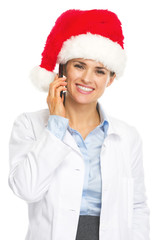 Smiling doctor woman in santa hat talking cell phone