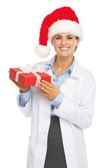 Happy doctor woman in santa hat holding christmas present box