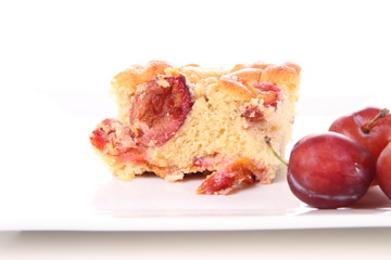 Plum pie decorated with plums on a white plate
