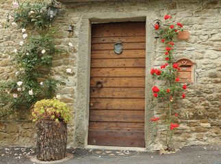front door decorated with climbing roses in old tuscan village