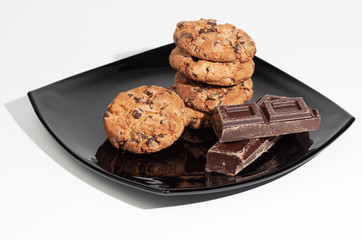 Some chocolate cookies on black plate isolated on white