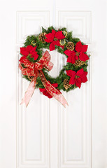 Christmas flower wreath hanging on white wood door