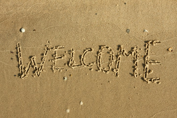 Word welcome written on the sand