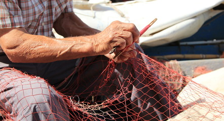 Mani che rammendano la rete da pesca