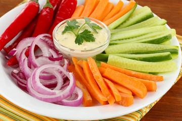 Assorted raw vegetables sticks in plate on wooden table close