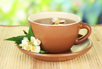 Cup of tea with jasmine, on bamboo mat, on bright background