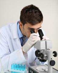 Young laboratory scientist looking at microscope in lab