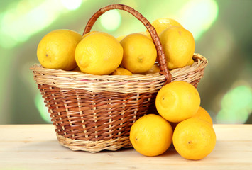 Ripe lemons in wicker basket on table on bright background