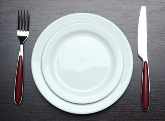 Knife, color plate and fork, on wooden background