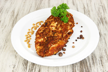 Roasted chicken fillets on white plate, on wooden background