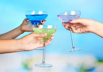 Cocktails in hands on pool background