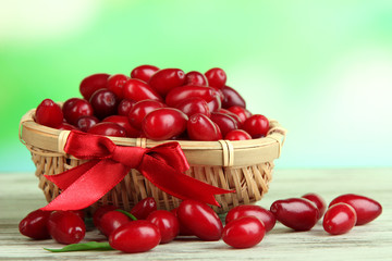 Fresh cornel berries in basket on wooden table