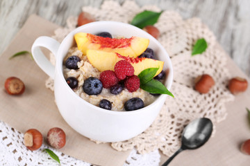 Oatmeal in cup with berries on napkins on wooden table