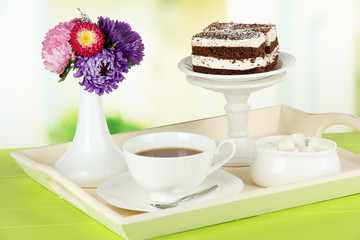 Fototapeta na wymiar Cup of tea with cakes on wooden tray on table in room