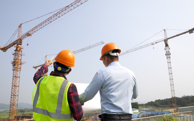 Site manager and construction worker checking plans