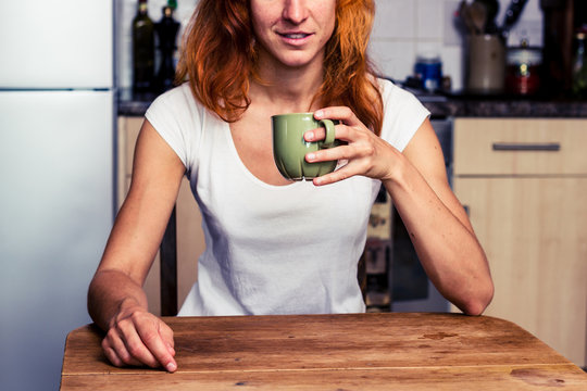 Woman drinking from cup in her kitchen