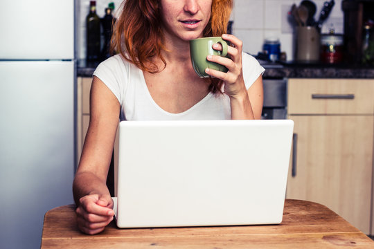 Woman drinking coffee and working on laptop