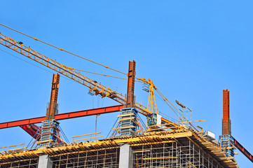 Crane and building construction site against blue sky
