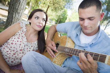 Mixed Race Couple at the Park Playing Guitar and Singing