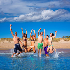 Happy excited teen boys and girls beach jumping
