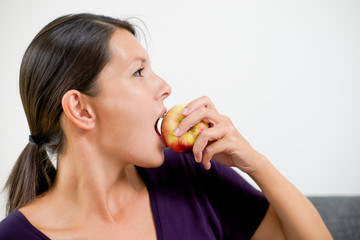 Attractive woman biting a fresh red apple