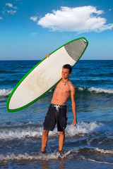 Boy teen surfer holding surfboard in the beach