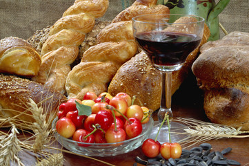 Still life with bread, cherry, and wine on wooden table.