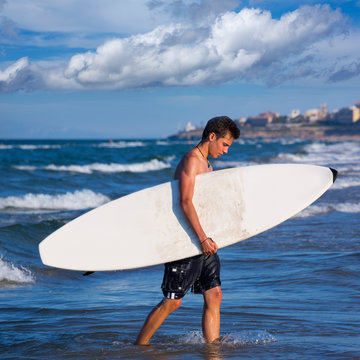 boy surfer holding surfboard caming out from the waves