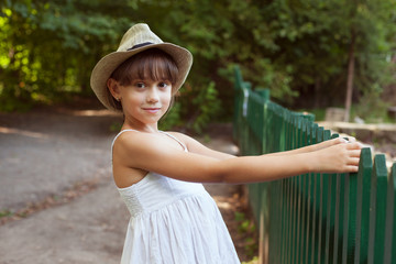 Girl in the hat next to a fence