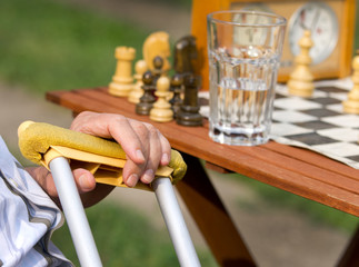 Pensioner with crutches playing chess
