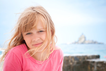 Portrait of smiling little blond girl in pink on the seacoast
