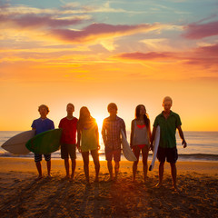 Surfers boys and girls group walking on beach